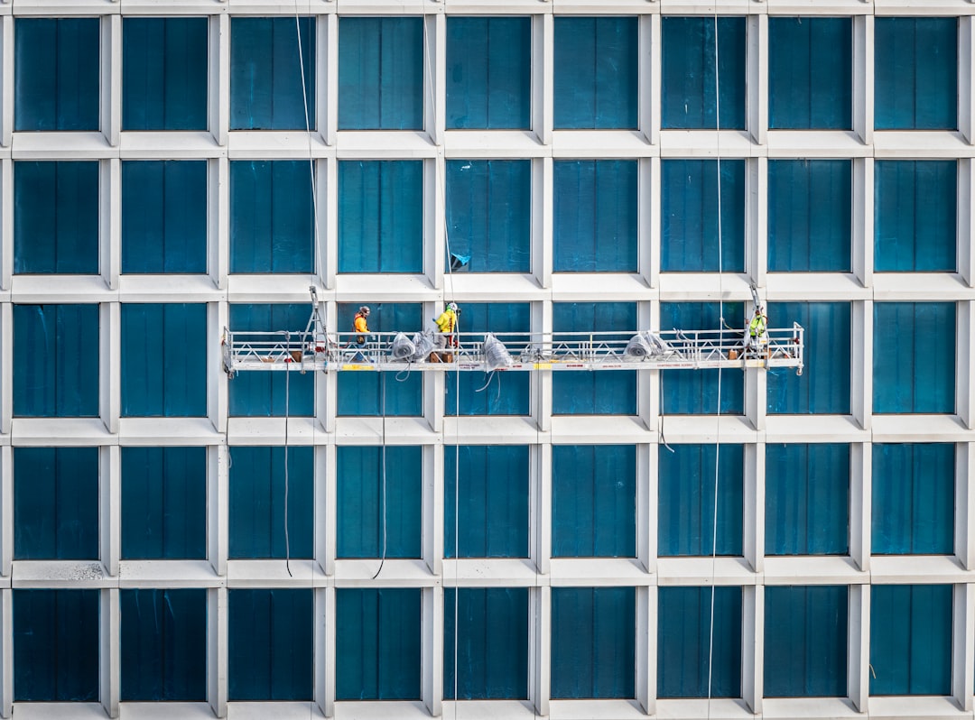 Construction workers hang from the side of a newly constructed building.